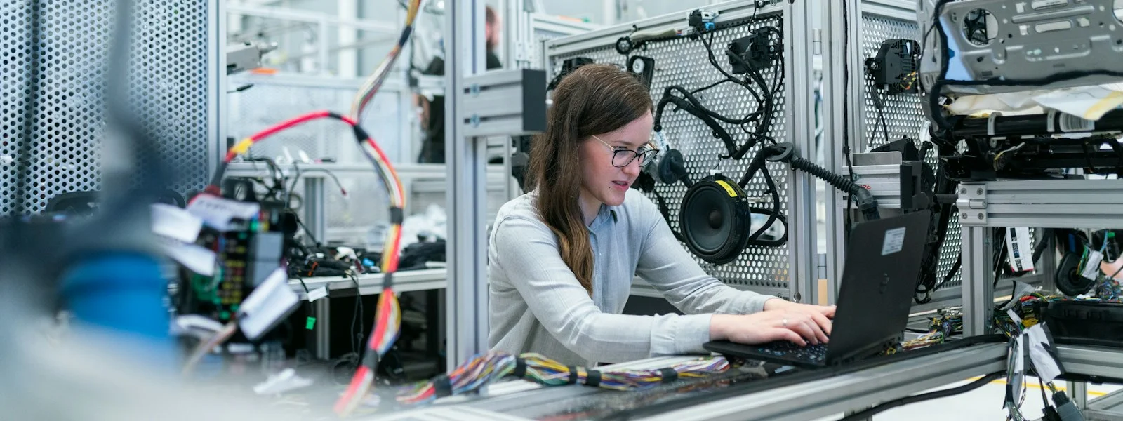 女工程師在智慧工廠產線與工業機台旁使用筆電進行 AI 導入評估