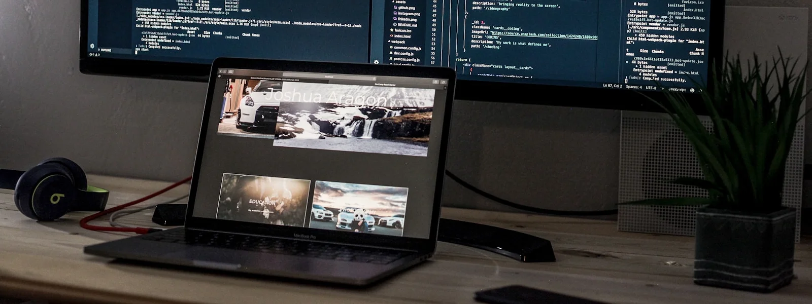 A laptop and a wide monitor displaying lines of code on a desk