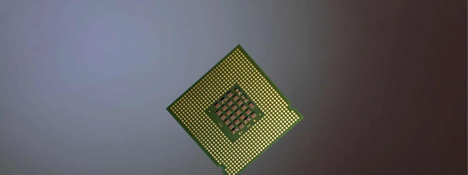 A computer processor held by black tweezers against a neutral background